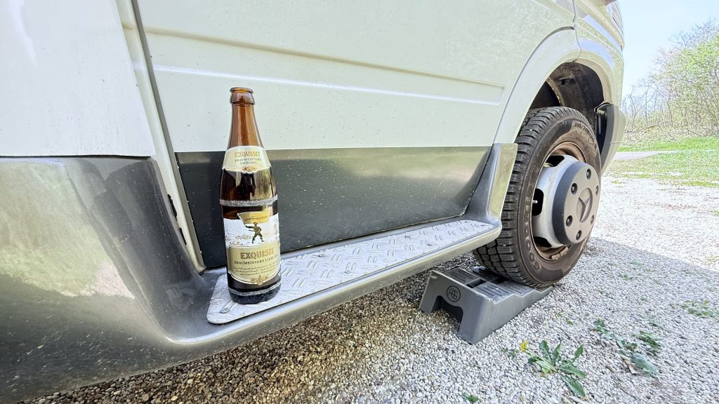 Eine volle Bierflasche steht auf der Trittstufe des Wohnmobils